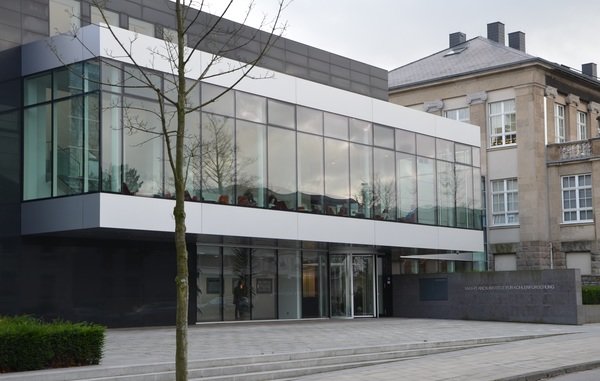 The Max-Planck-Institut für Kohlenforschung entrance features a contemporary glass design, adjacent to a stone building facade.