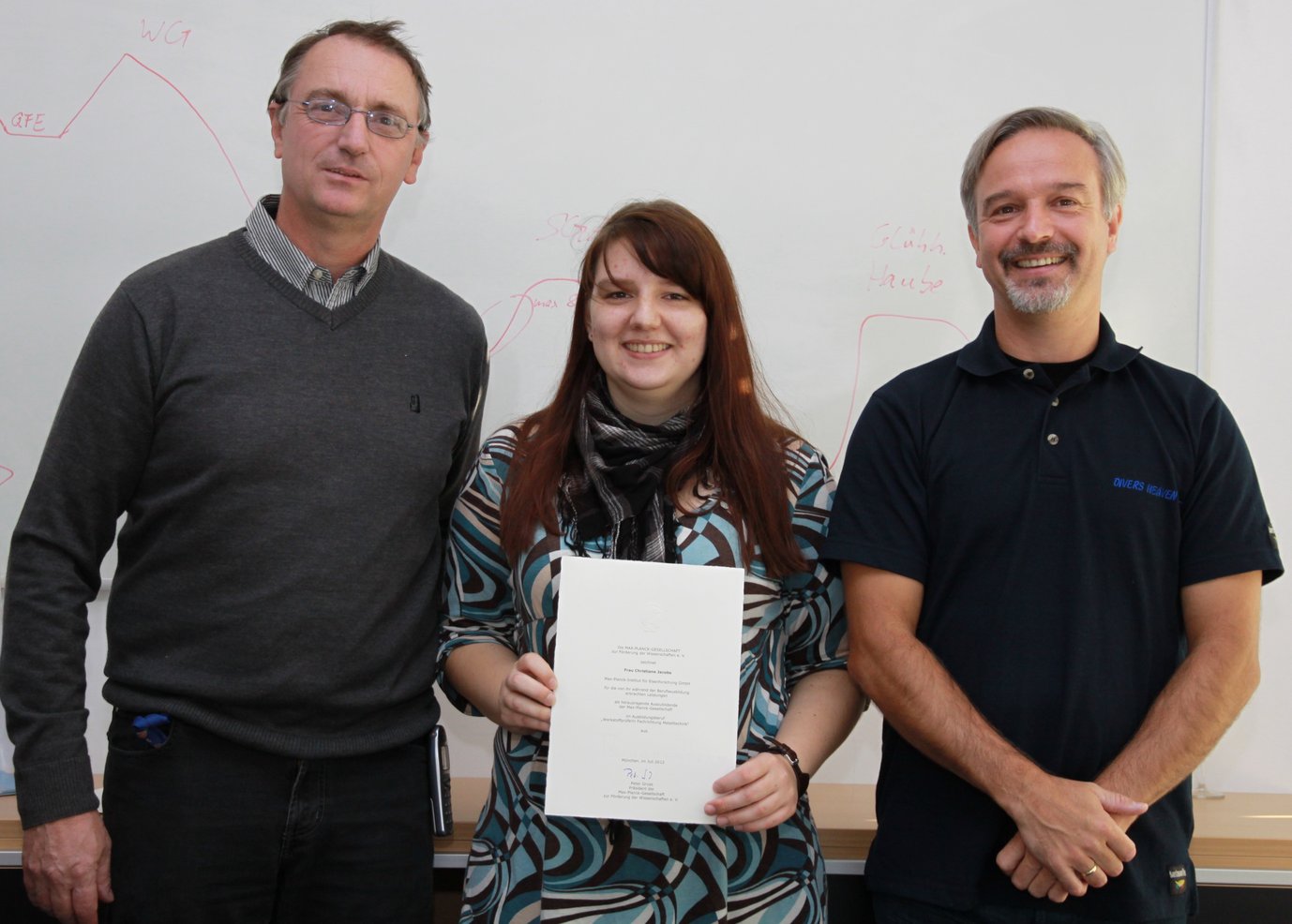 Christiane Jacobs bei der feierlichen Übergabe der Urkunde mit Prof. Raabe, Vorsitzender der Geschäftsführung (rechts), und Herbert Faul (links), Ausbilder im Bereich Werkstoffprüfung am MPIE.