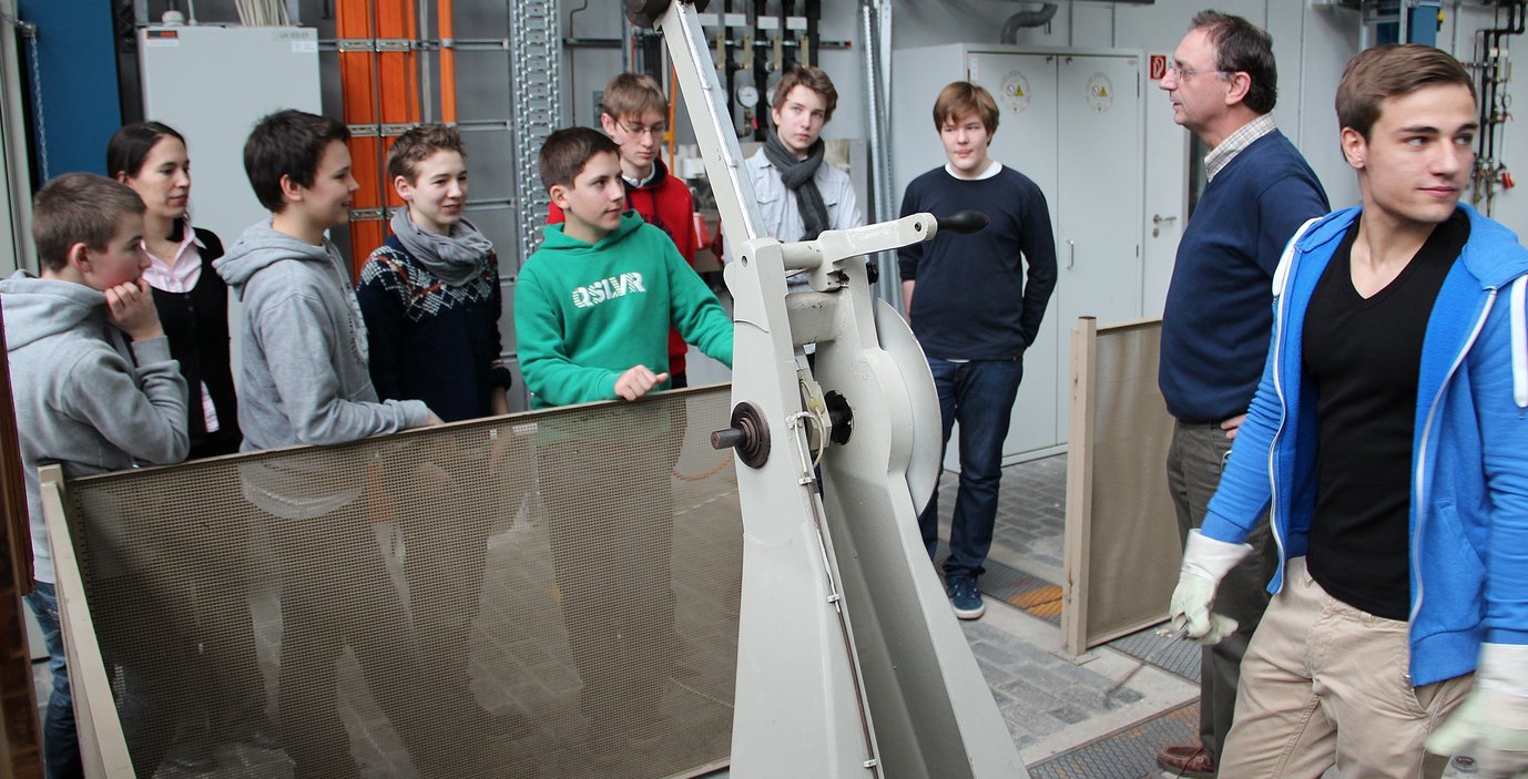 Herr Faul (Zweiter von rechts), Ausbilder am MPIE, erklärt einigen Schülern des TFG die Funktionsweise des Kerbschlagbiegeversuches.