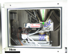 Fig. 1 Asmec Unat II installed in a Jeol JSM 6490 SEM, our standard testing rig for micron sized samples. The counterparty (e.g. a diamond or tungsten tip) is marked with “Indentation”, with the sample support pin opposite of it. Sample and indenter can independently be moved along 4 axis with submicron resolution. In addition, the entire setup can be oriented with 5 additional axis, which allows for versatile experimental setups (EBSD, ECCI)