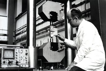 Systematische Untersuchungen zu Rissbildung und Bruch am Max-Planck-Institut für Eisen-forschung: eine zwischen zwei Spannbacken eingespannte Kompaktprobe mit vorgearbeiteter Kerbe wird Zug und Biegung ausgesetzt. Die dabei stattfindende Rissaufweitung und die Zugkraft werden elektronisch gemessen, 1975. Systematische Untersuchungen zu Rissbildung und Bruch am Max-Planck-Institut für Eisen-forschung: eine zwischen zwei Spannbacken eingespannte Kompaktprobe mit vorgearbeiteter Kerbe wird Zug und Biegung ausgesetzt. Die dabei stattfindende Rissaufweitung und die Zugkraft werden elektronisch gemessen, 1975.