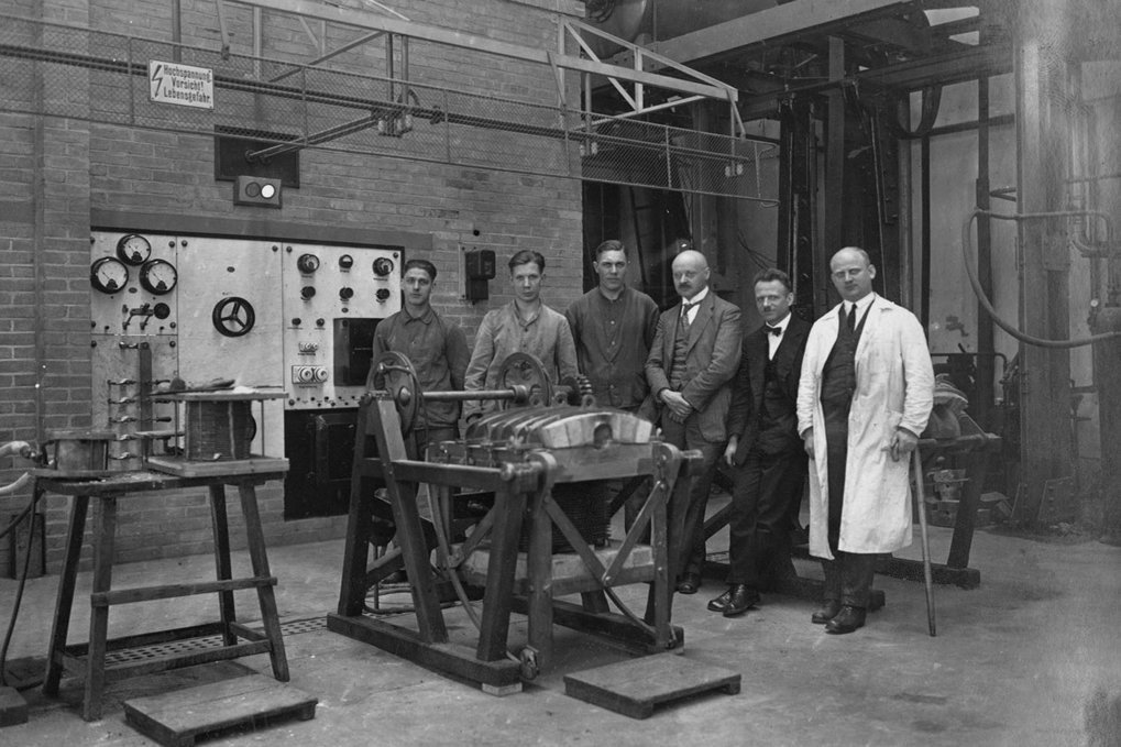 Men in industrial attire beside machinery.