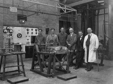 Men in industrial attire beside machinery.