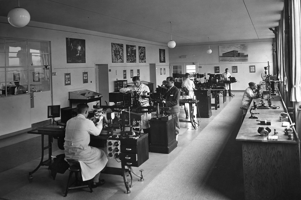 Scientists working in a laboratory filled with equipment and desks.
