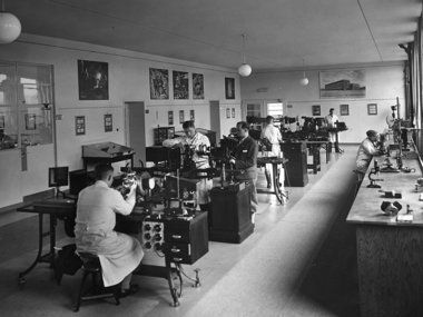 Scientists working in a laboratory filled with equipment and desks.