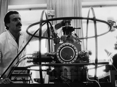 Scientist with complex machinery in a lab setting.