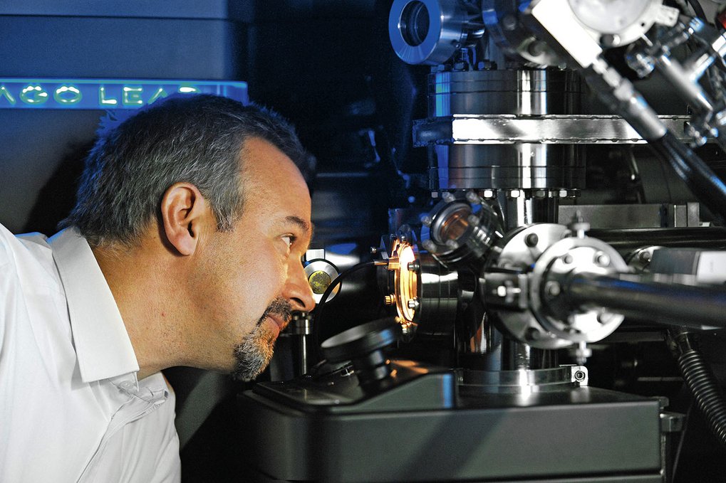 Man examining complex machinery with metallic components.
