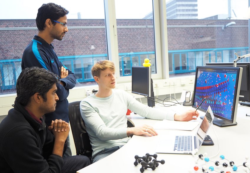 Dr. Michael Ashton (on the right) explaining his work about etching reactions for MAX compositions to his colleagues Sudarsan Surendralal (in the front left) and Ankit Gupta, doctoral students in the Computational Materials Design department. Dr. Michael Ashton (on the right) explaining his work about etching reactions for MAX compositions to his colleagues Sudarsan Surendralal (in the front left) and Ankit Gupta, doctoral students in the Computational Materials Design department.