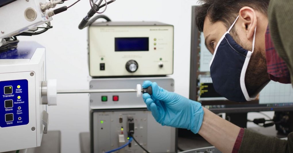 Person in the lab with blue glove and face mask