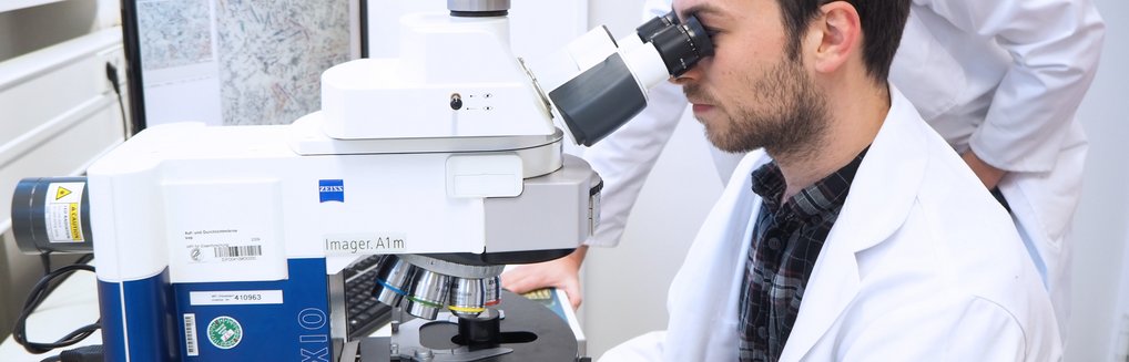 Person schaut in Mikroskop.