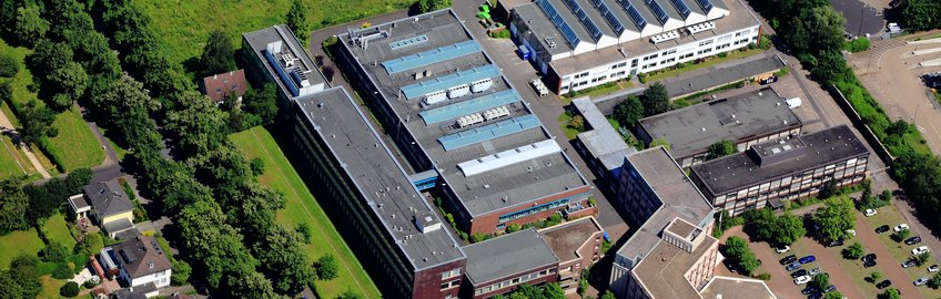 Anfahrt Gesamtansicht eines Gebäudekomplexes mit Bäumen auf der linken Seite