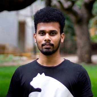 Individual stands outdoors, wearing a black t-shirt with a white bear silhouette, surrounded by greenery and trees.