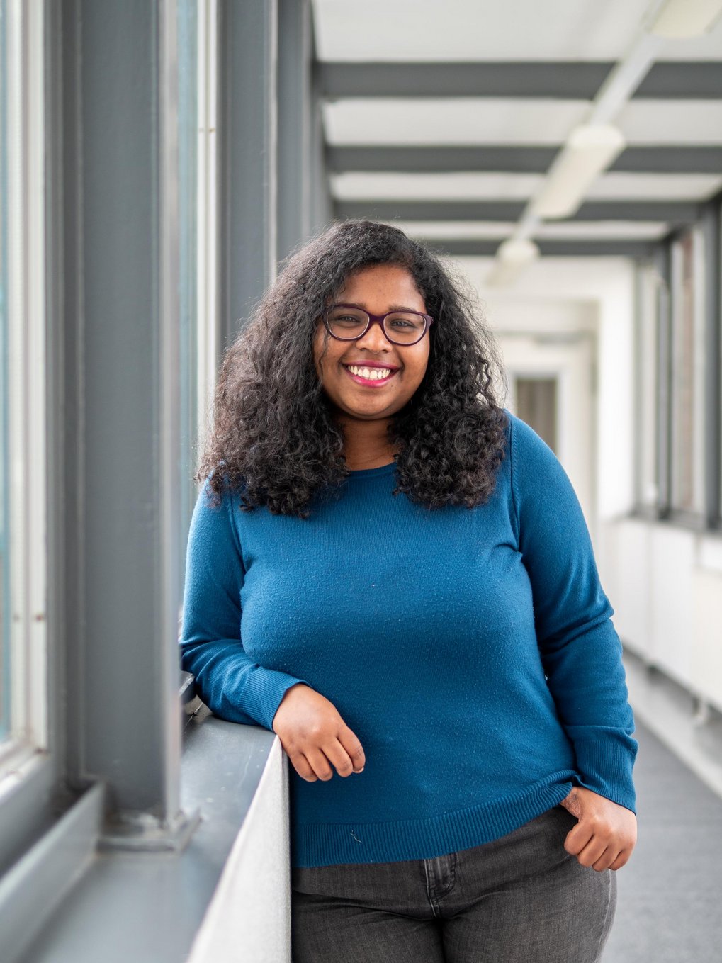 Person with blue pullover leaning at window sill