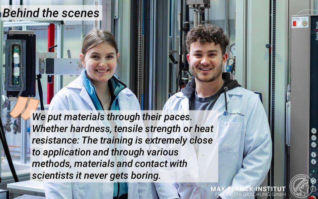 Two scientists in lab coats with equipment in the background.