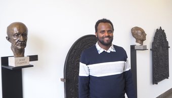 A row of busts, including one of Max Planck, on black plinths next to ornately decorated wall panels.