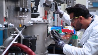 Ubaid Manzoor, PhD researcher at MPI-Susmat and first author of the Nature publication, using an electric arc furnace to reduce low-grade nickel ores with hydrogen plasma. Person in a lab coat and with protective glasses looking into the analytic chamber of an electric arc furnace.