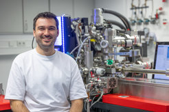 Scientific lab with technological equipment. Dr. Tim M. Schwarz is sitting in front of the atom probe.