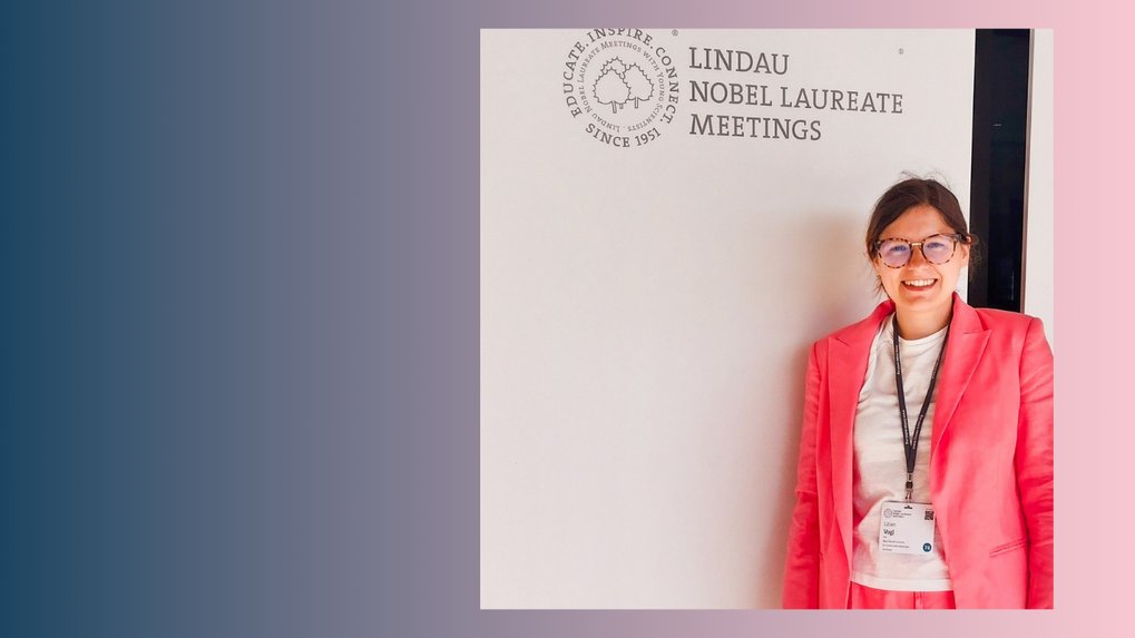 Person in pink suit in front of beige wall with logo.