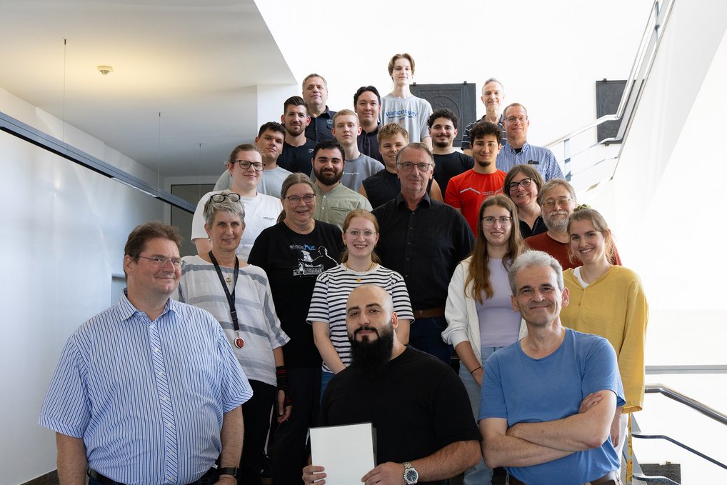Trainees, trainers and management of MPI-SusMat celebrating being awarded the Apprenticeship Award 2025 for the institute. Group of people in casual clothing standing on stairs.