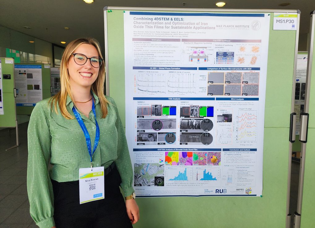 Nina Kosian, Doktorandin am Max-Planck-Institut für Nachhaltige Materialien, wurde mit einem Posterpreis bei der Microscopy Conference MC2025 ausgezeichnet. In ihrer Arbeit forscht sie zu Dünnschichten aus Eisenoxiden - potentielle Kandidaten für Elektrokatalysatoren zur effizienten Herstellung von grünem Wasserstoff. Person steht neben einem Poster über Dünnschichten aus Eisenoxiden, während einer wissenschaftlichen Konferenz.