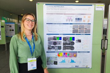 Person steht neben einem Poster über Dünnschichten aus Eisenoxiden, während einer wissenschaftlichen Konferenz.