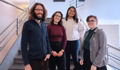 A group of four people in a building smiling at the camera.