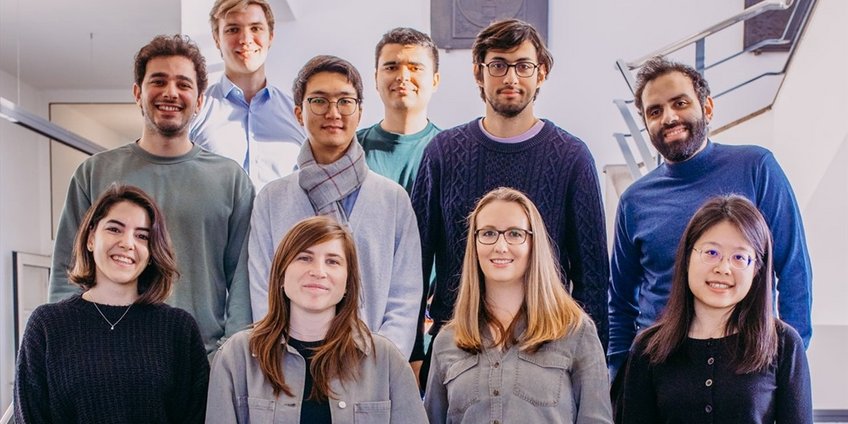 PhD Representatives A group og ten people in a modern building, standing in three rows, looking at the camera