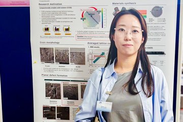 Person standing in front of a poster at a scientific conference.