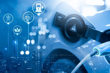 Electric car being charged. The background shows icons for wind turbines, sustainability, recycling etc.