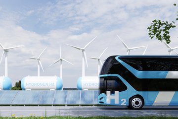 Hydrogen bus near wind turbines, solar panels and hydrogen storage tanks.