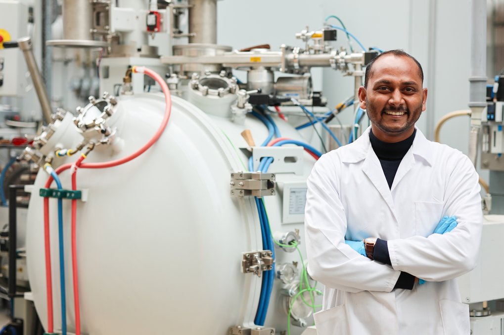 Man in lab coat in front of scientific device.