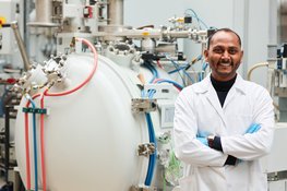 Man in lab coat in front of scientific device.