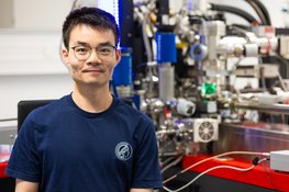 Man in blue t-shirt sitting in scientific laboratory.