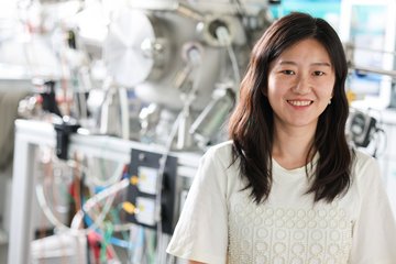 Woman in a laboratory with scientific equipment in the background.