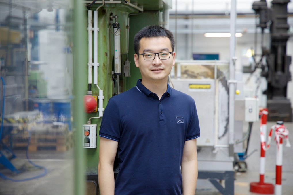 Man stands in an industrial hall. In the background is a forging hammer.