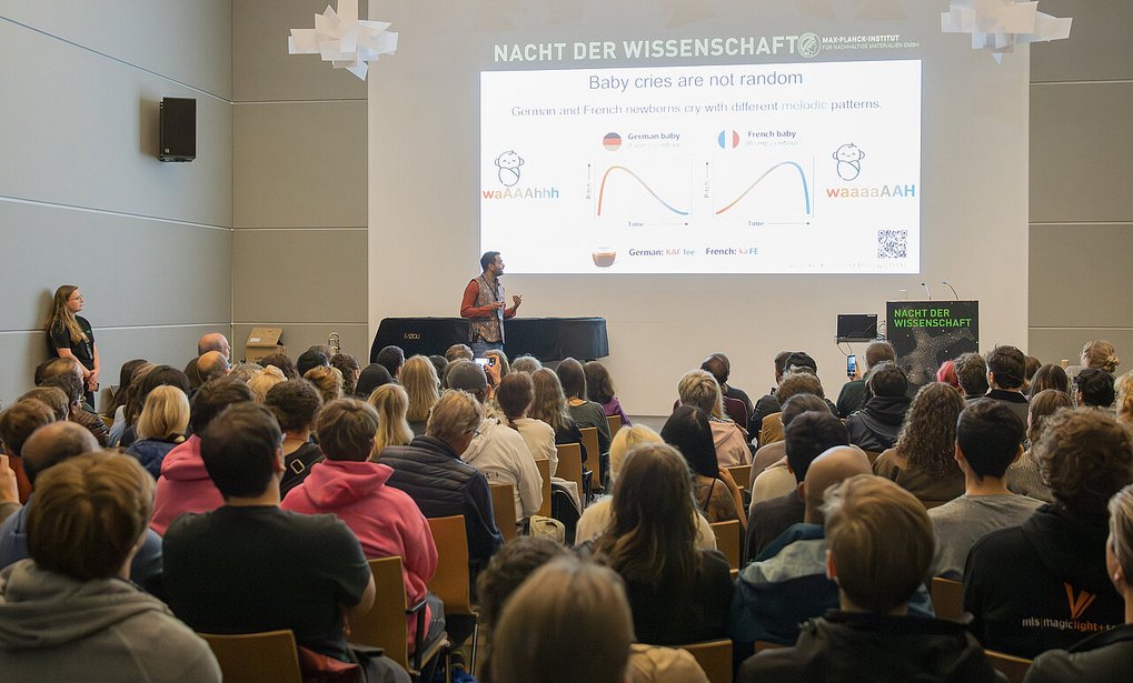 Personen hören einem Vortrag zu und schauen auf eine Präsentation.
