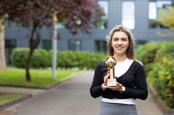 Dr Tugce Beyazay, project group leader, won the Science Slam during the Düsseldorf Night of Science 2026, with her slam about recovering metals from industrial waste with the help of hydrogen. Woman holds a trophy in her hand and is standing in front of dark building.