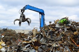 A pile of metal scrap with a crane in the background.
